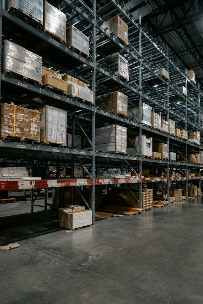 services-04 A well-organized industrial warehouse with stacked shelves and various pallets for efficient storage.