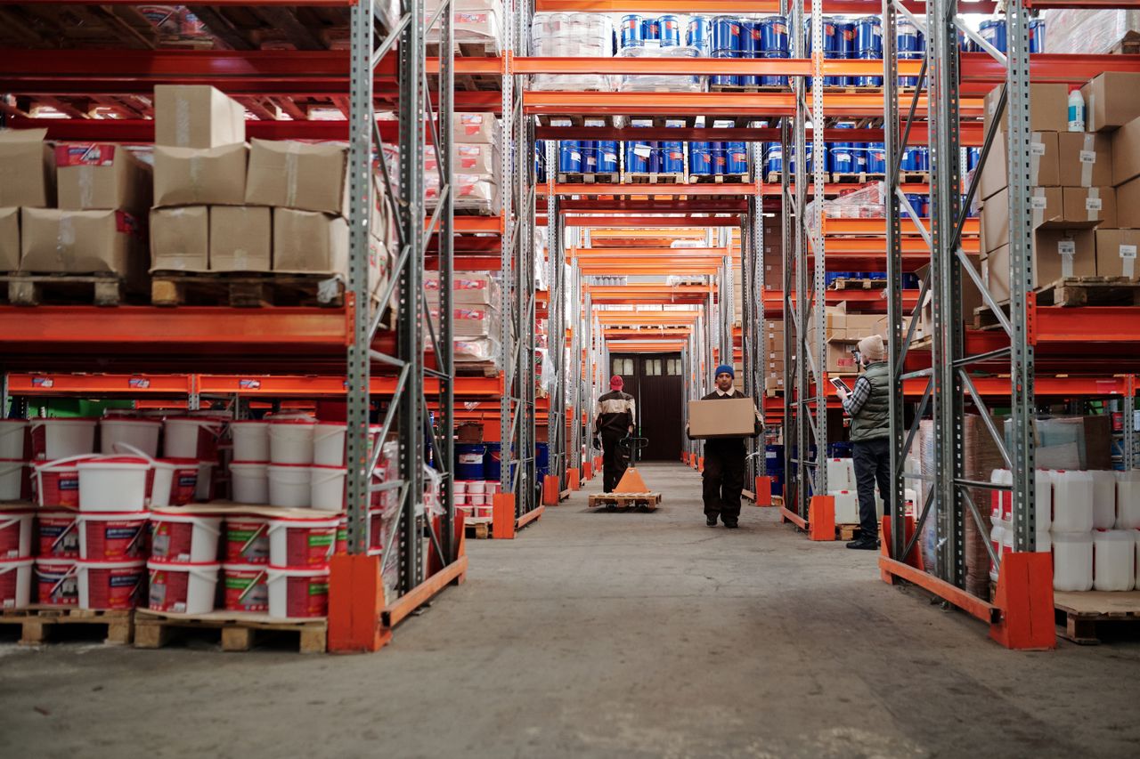 Mastering the First Impression: Your intriguing post title goes here Warehouse interior showing workers handling boxes and organized shelves filled with products.